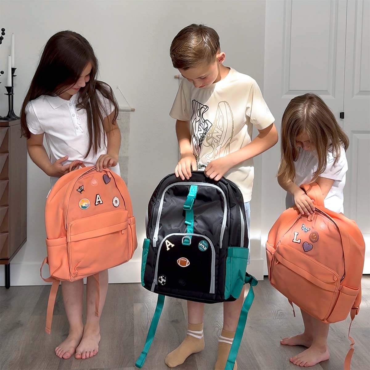 Three kids looking at their new backpacks